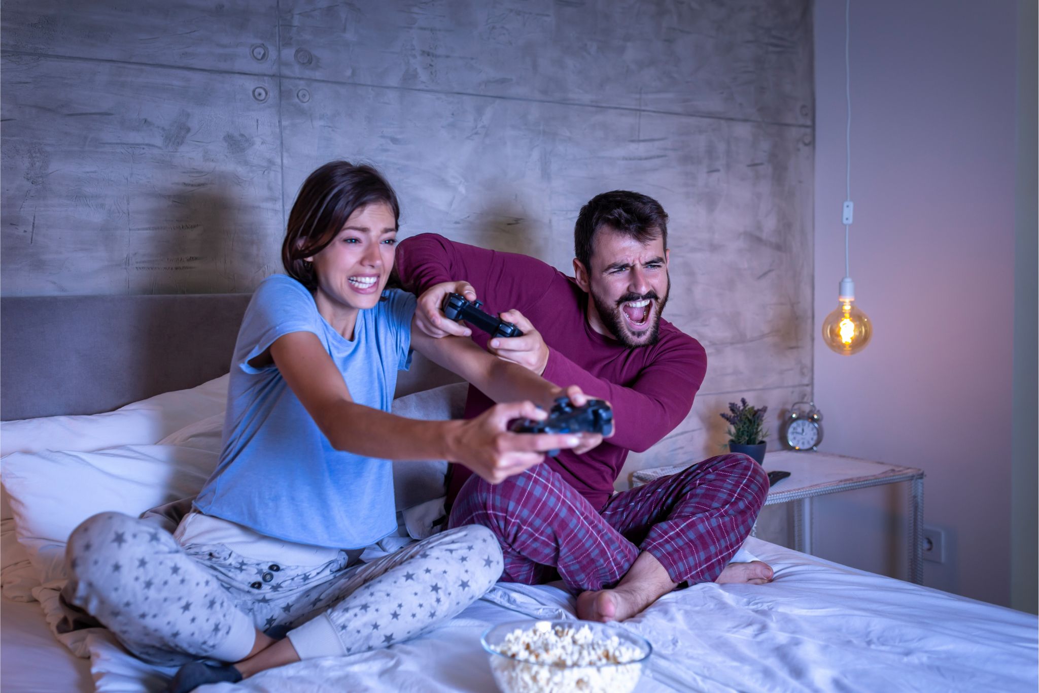 Pareja jugando videojuegos en la cama